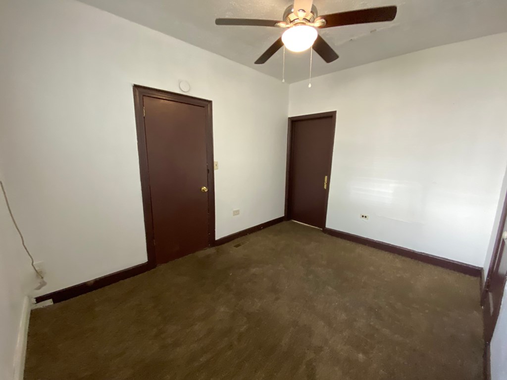 A room with a ceiling fan and two doors.