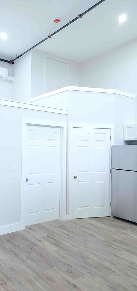 A kitchen with white doors and a wooden floor.