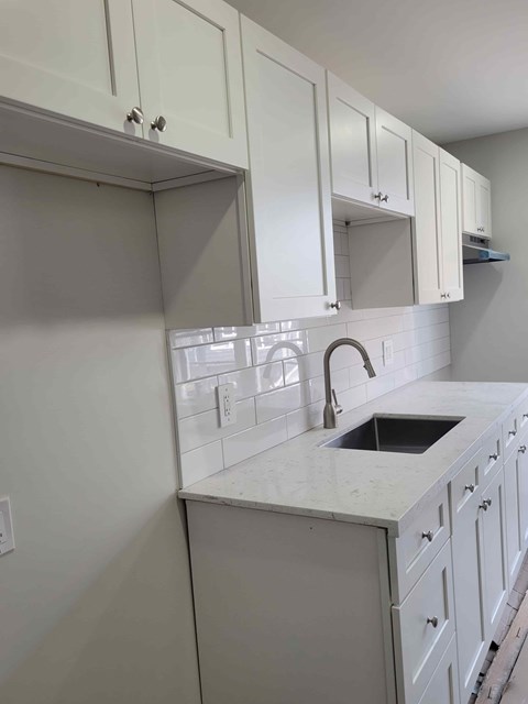 A kitchen with white cabinets and a white countertop.