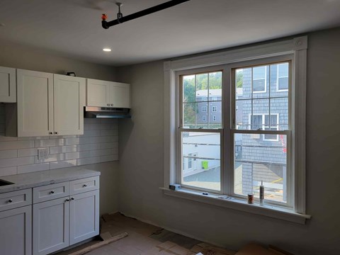 A kitchen with white cabinets and a window overlooking a street.