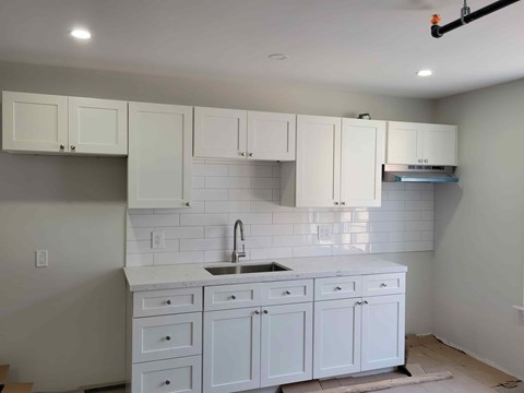 A kitchen with white cabinets and a white countertop.