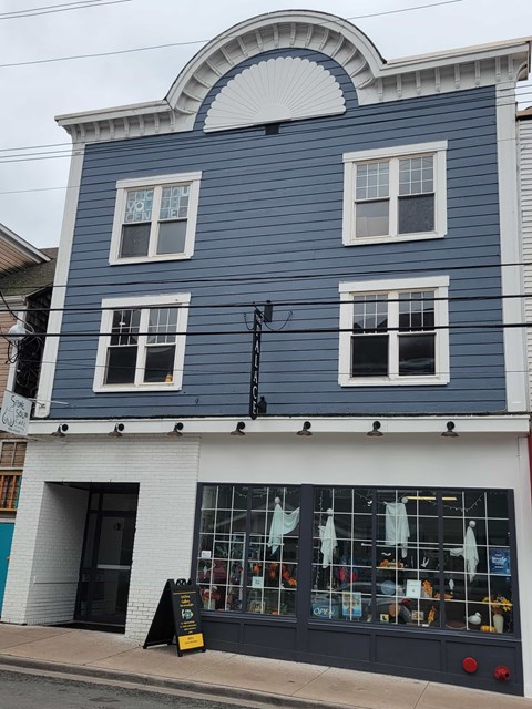A blue building with a white trim and a black awning.