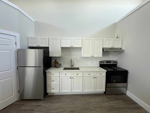 A kitchen with white cabinets and a stainless steel refrigerator.