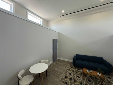 A living room with a blue couch, a white chair, and a small table.
