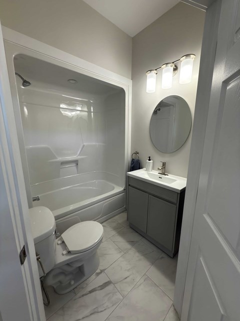 A white toilet sits next to a bathtub in a bathroom.
