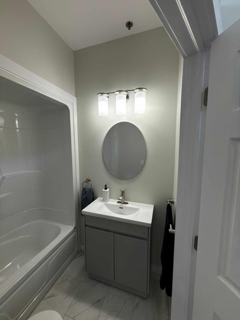 A bathroom with a white sink and a round mirror.