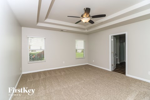 A spacious room with a ceiling fan and carpeted floor.