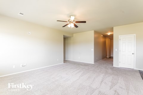 A spacious room with a carpeted floor and a ceiling fan.