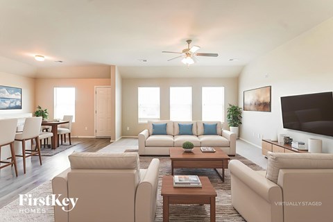 A living room with a couch, chairs, and a ceiling fan.