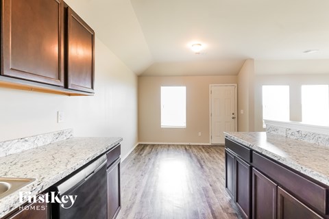 A kitchen with dark brown cabinets and marble countertops.