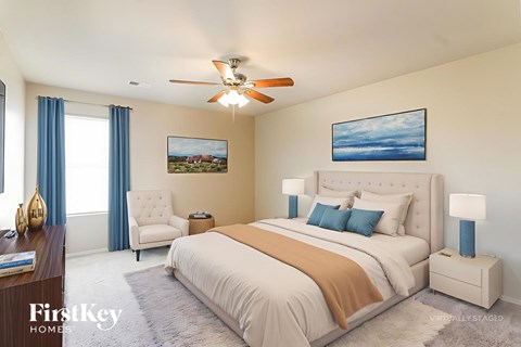 A bedroom with a large bed, a ceiling fan, and a painting on the wall.