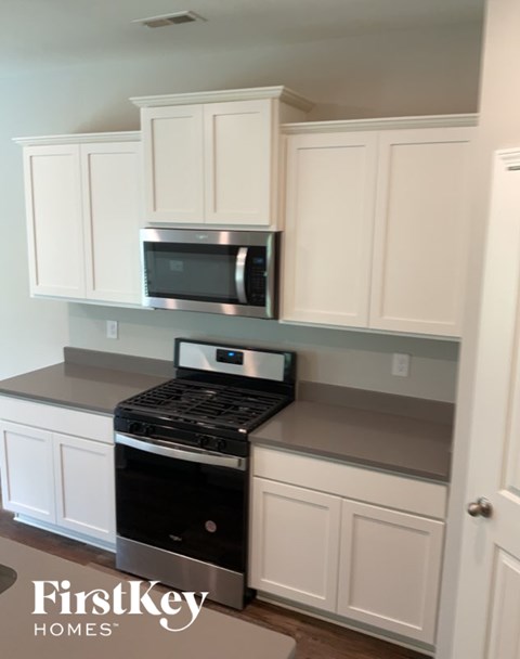 A kitchen with white cabinets and a black stove top oven.