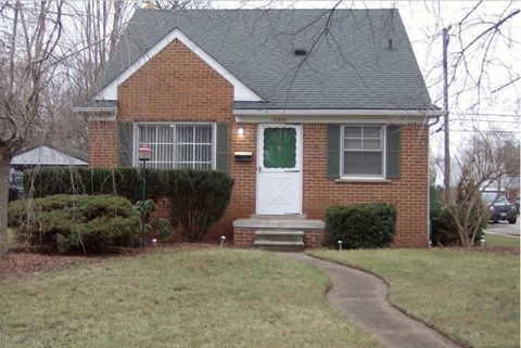 A brick house with a white door and green shutters.