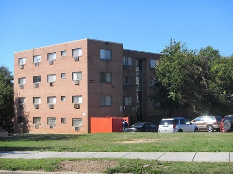 A tall brick apartment building with a red garage door in front.
