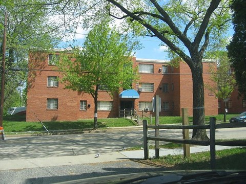 A red brick building with a blue awning sits behind a wooden fence.