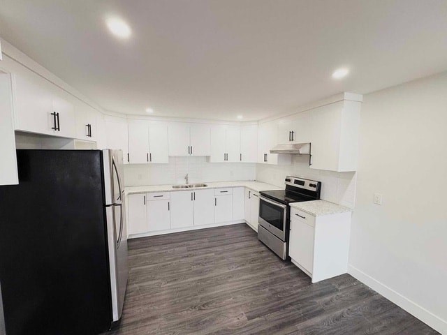 A black refrigerator is in the corner of a white kitchen.