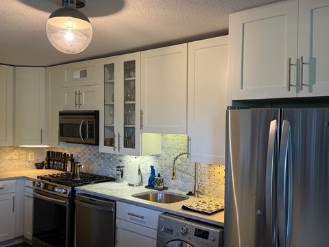 A kitchen with white cabinets and a stainless steel refrigerator.