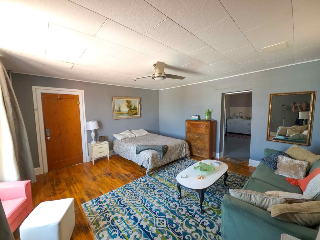 A room with two beds, a couch, and a rug.