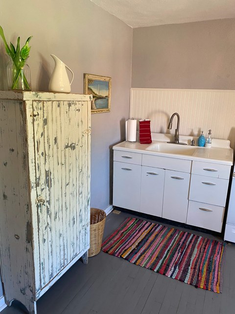 A white cabinet with a sink and a vase on top of it.