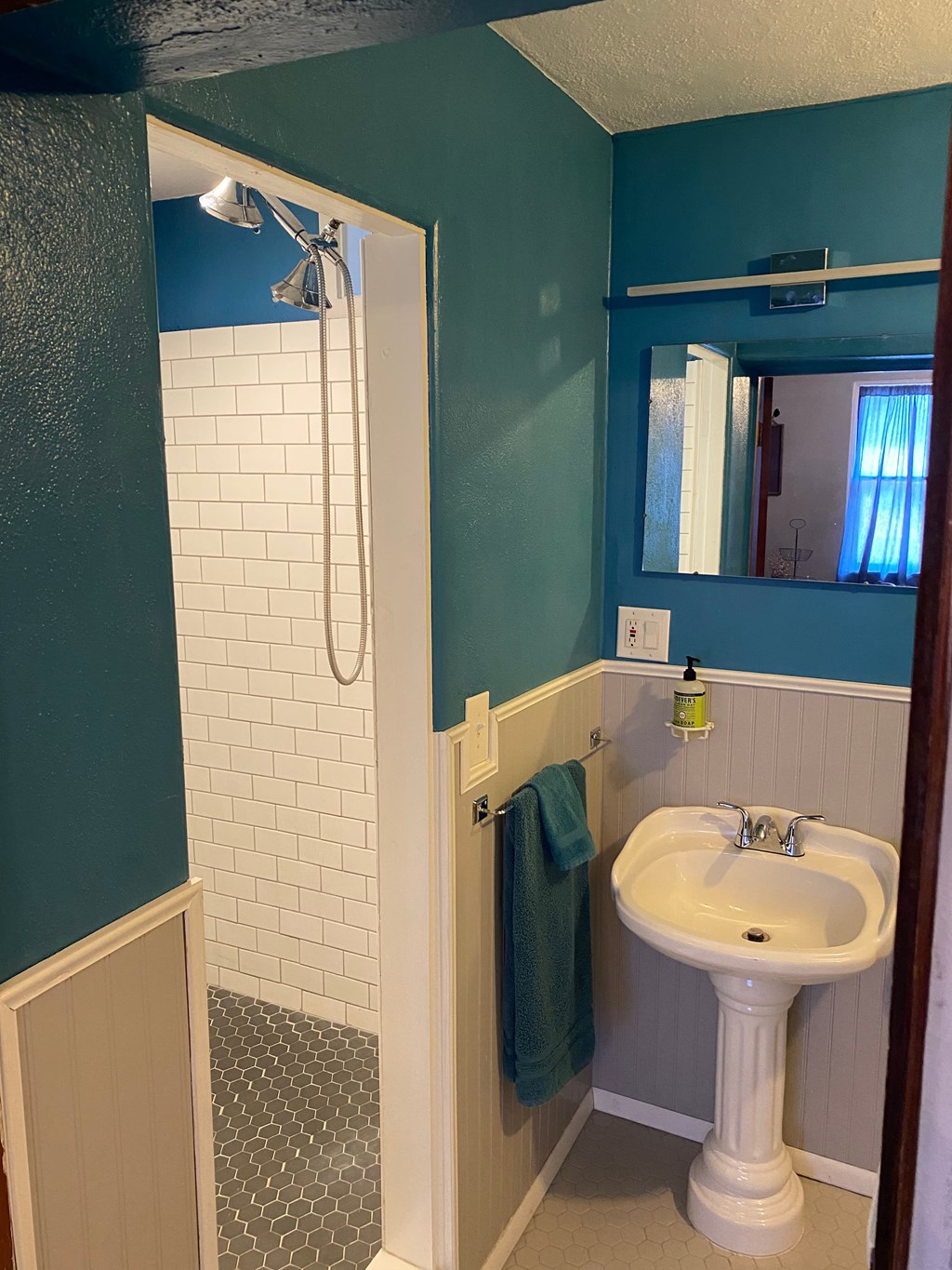A white pedestal sink with a green towel on a blue wall.