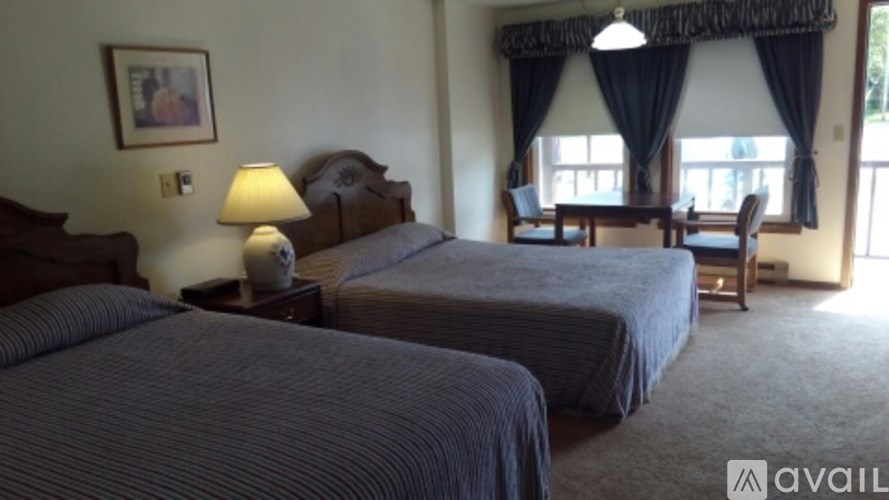 Two beds in a room with a table and chairs.