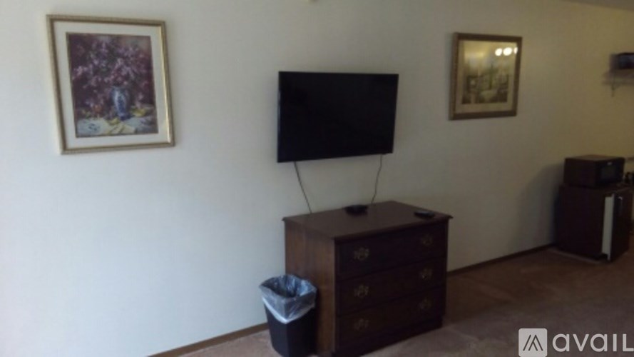 A black television sits on a wooden cabinet in a room with a painting on the wall.