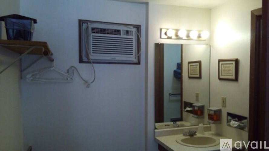 A bathroom with a sink, mirror, and a fan on the wall.
