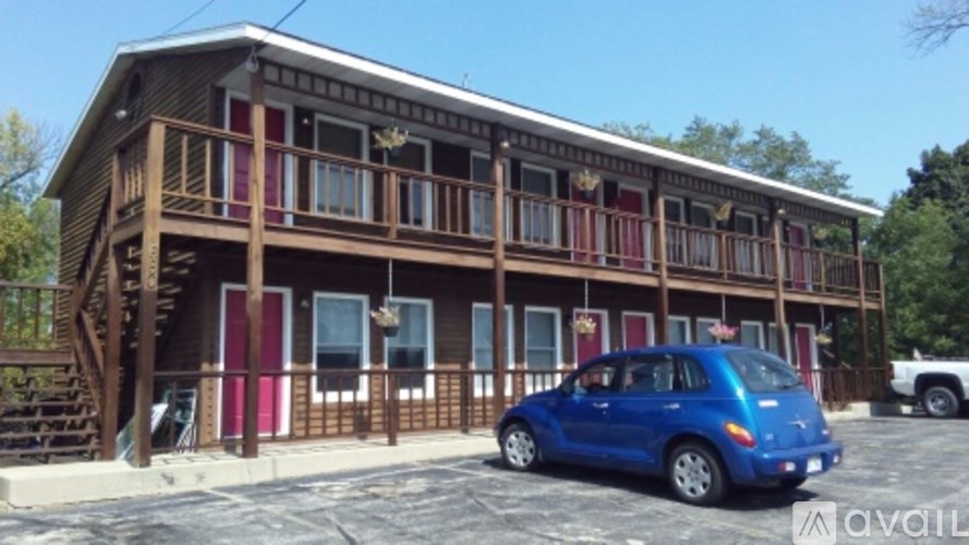 A blue car is parked in front of a wooden building.