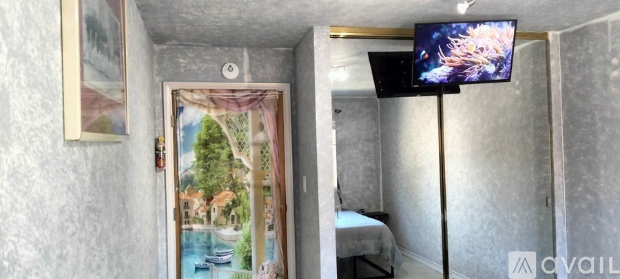 A bedroom with a bed, a television, and a painting of a landscape on the wall.