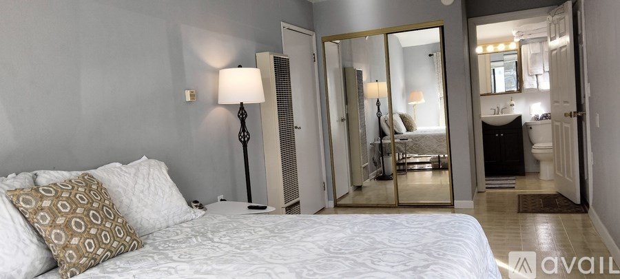 A bedroom with a bed, a lamp, and a mirror.