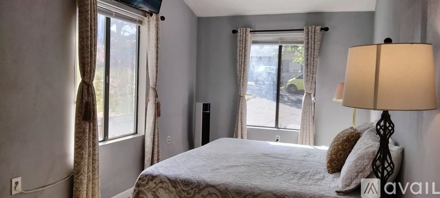 A bedroom with a large bed and a window with curtains.