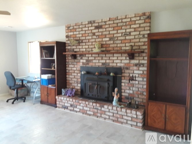 A room with a brick fireplace and a desk with a chair.