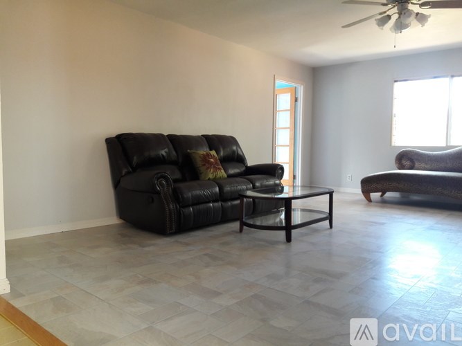A living room with a black leather couch and a glass coffee table.