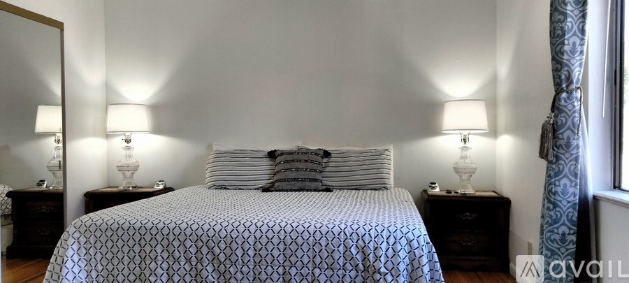 A bedroom with a bed, two lamps, and a window with curtains.