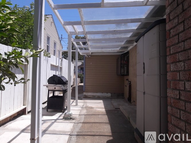A patio with a white pergola and a black grill.