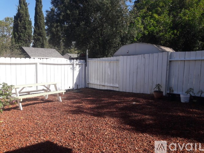 A backyard with a white fence and a picnic table.