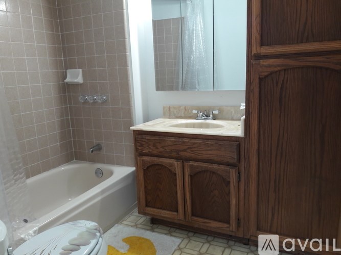 A bathroom with a tub, sink, and wooden cabinet.