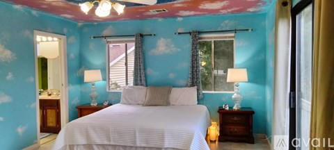 A bedroom with a blue wall and a wooden dresser with a mirror on top.
