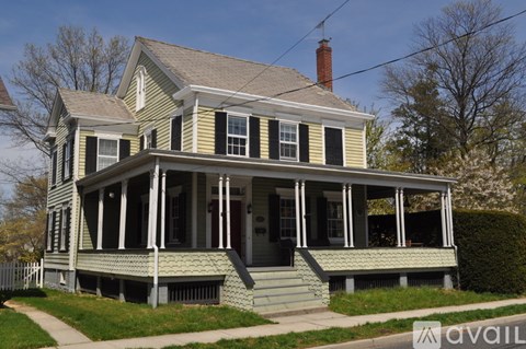 A two-story house with a porch and a chimney.
