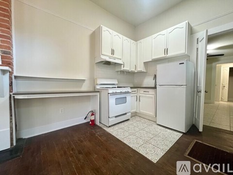 A kitchen with white cabinets and a red fire extinguisher on the floor.