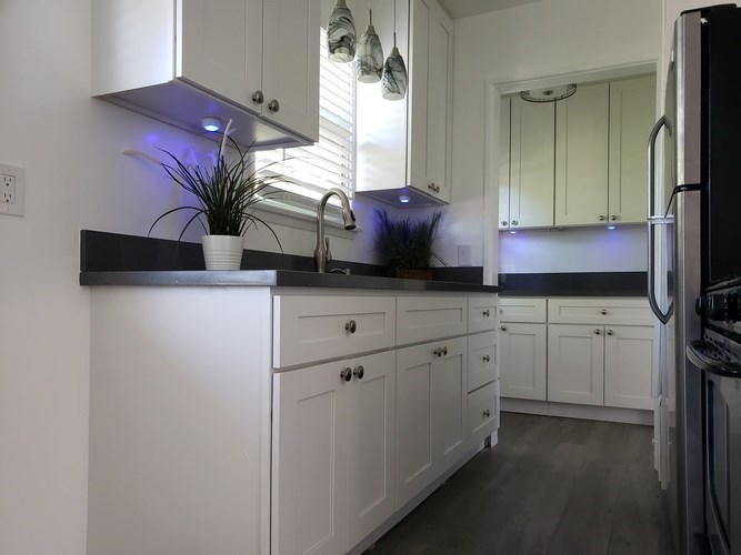 A kitchen with white cabinets and a black countertop.