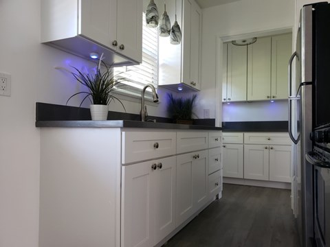 A kitchen with white cabinets and a black countertop.