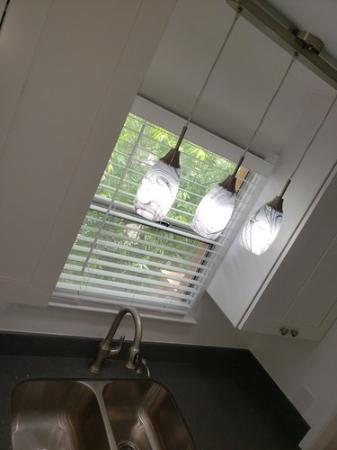 A kitchen with a sink and a window with blinds.