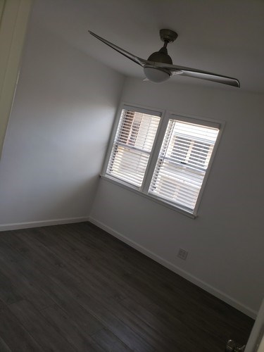 A room with a ceiling fan and a window with blinds.