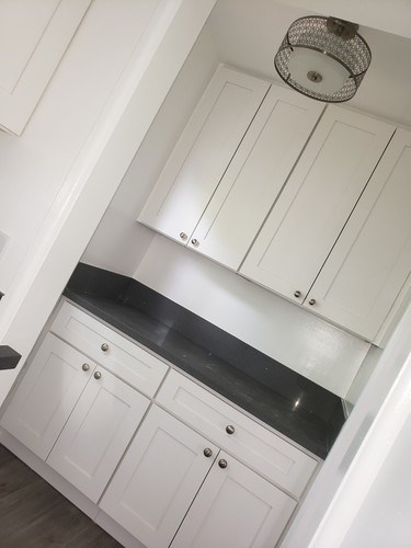 A kitchen with white cabinets and a black countertop.
