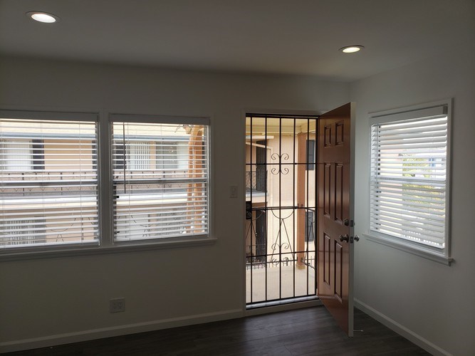 A room with a wooden door and a window with blinds.