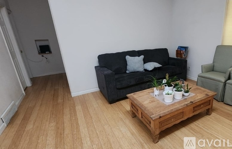 A living room with a black couch, wooden coffee table, and a green armchair.