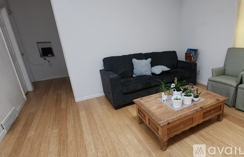 A living room with a black couch, wooden coffee table, and a green armchair.