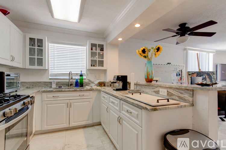 A kitchen with white cabinets and a marble countertop.