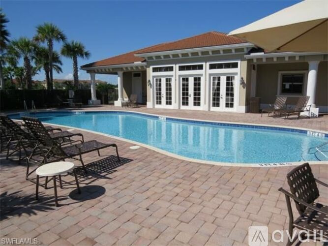 A pool surrounded by chairs and a house with a patio.